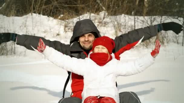 Far och dotter sitter på snön — Stockvideo