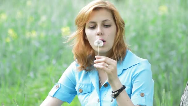 Schönes Mädchen bläst auf einer Löwenzahnblume — Stockvideo