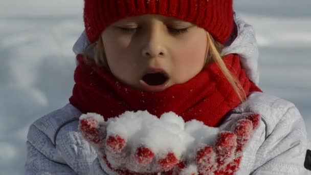 Маленькая девочка, выдувающая снег — стоковое видео
