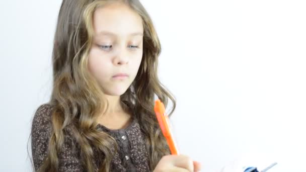 Маленькая девочка пишет в блокноте — стоковое видео