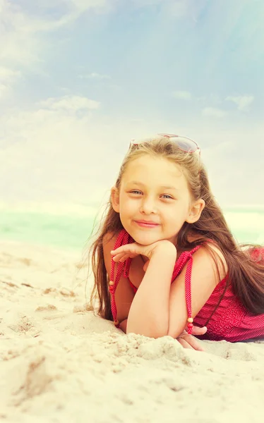 Schattig klein meisje liggend op het zand in de buurt van de zee — Stockfoto