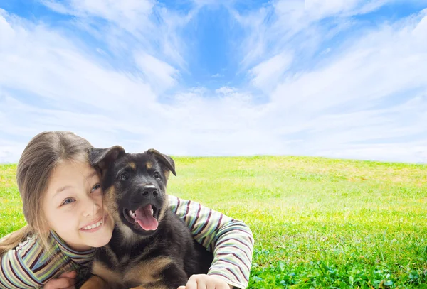 Positive kid with a puppy on a green lawn — Stock Photo, Image