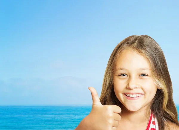 Bonita rindo menina mostra seu polegar no fundo do mar — Fotografia de Stock