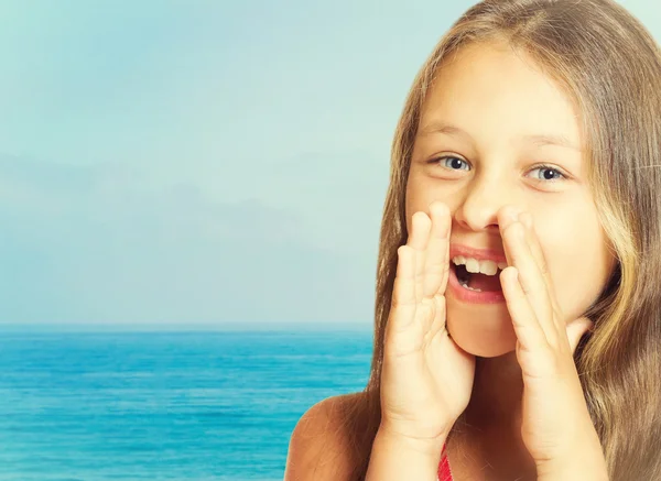 Girl speaks through cupped hands on sea background — Stock Photo, Image