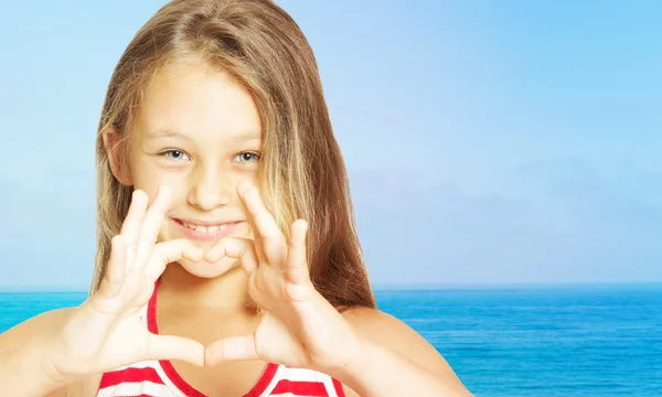 Bambina mostrando le mani del cuore sullo sfondo del se — Foto Stock