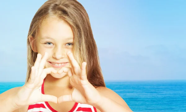 Niña mostrando las manos del corazón contra el fondo de la se — Foto de Stock