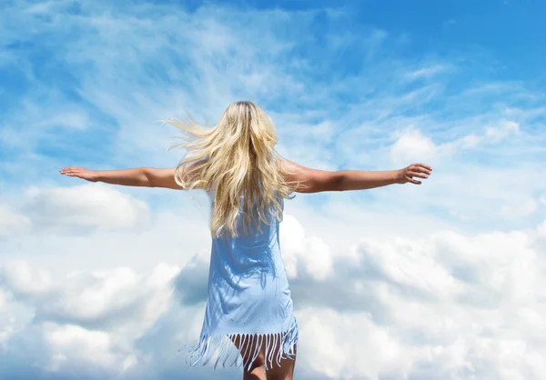 Girl in the blue dress standing arms outstretched against the sk — Stock Photo, Image