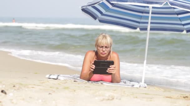 Oudere vrouw en een elektronische Tablet PC naar de zee — Stockvideo