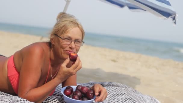 Vrouw eten een pruim op zee — Stockvideo