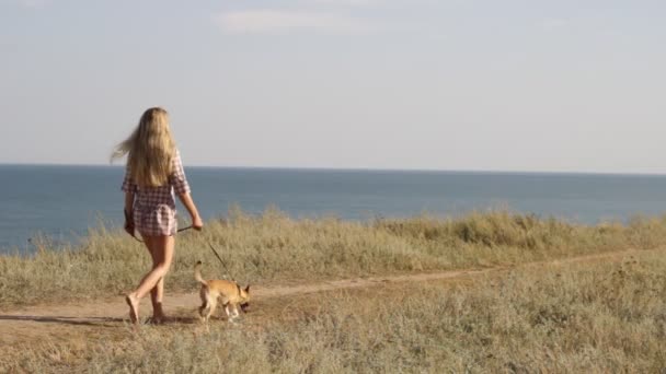 Joven mujer caminando con un perro cerca del mar — Vídeos de Stock