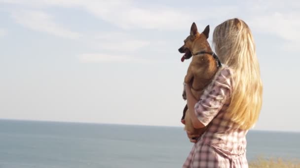 Ung kvinna och hund tittar på havet — Stockvideo