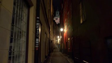 Stockholm 'ün merkezindeki eski dar sokağın gece aydınlanması. Eski kasaba. Mimarlık, eski evler, sokaklar ve mahalleler. İsveç. 4K 'da video, UHD