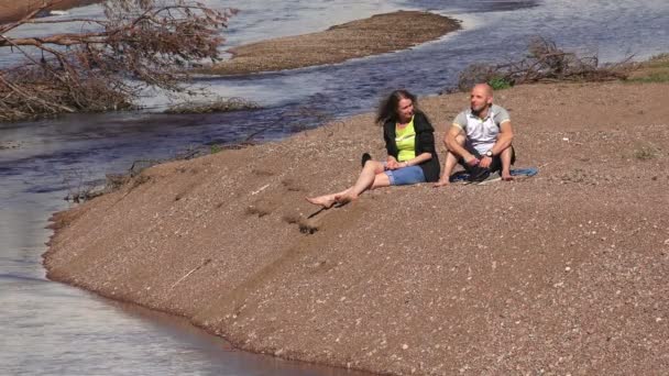 El hombre y la mujer un descanso en la orilla del río — Vídeo de stock