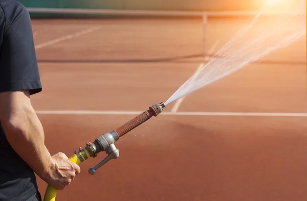 Person för underhåll sprinkler tennisbana — Stockfoto