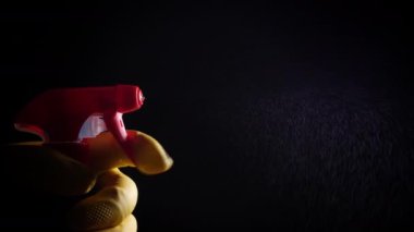 Karanlık bir arka planda sprey şişesi olan bir el.