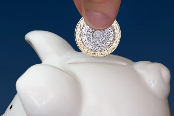 Male hand putting a coin into piggy bank — Stock Photo, Image