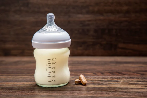 Small Baby Bottle Filled Milk Two Supplement Wood Background — Stock Photo, Image