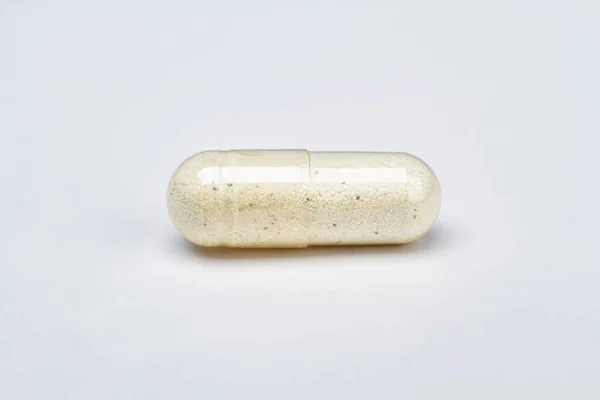 Ένα Διαφανές Χάπι Λευκό Συστατικό Και Μαύρη Σκόνη Λευκό Φόντο — Φωτογραφία Αρχείου