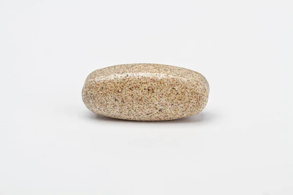 single brown natural supplement tablet against a white background