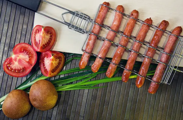 Grelha para salsichas e tomate, pão, cebola — Fotografia de Stock