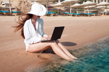 Kumda dizüstü bilgisayarı olan bir kadın dinleniyor ve serbest çalışıyor.