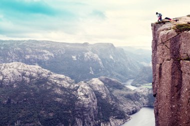 Aşağı bakan kadın Lysefjord 'un üzerindeki ünlü Preikestolen Kürsüsünde duruyor.