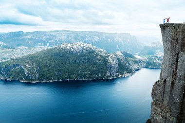 Lysefjord 'un üzerinde ünlü Preikestolen Minpit Rock' ta el ele tutuşan çift duruyor.