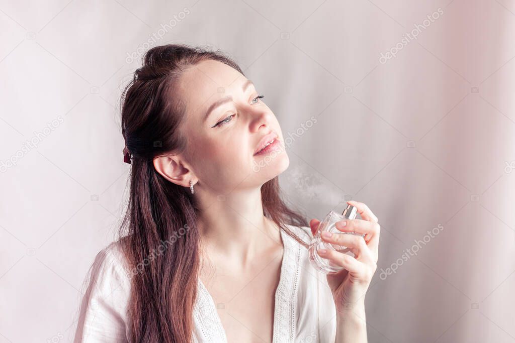 girl in a white dress sprays herself perfume on her neck