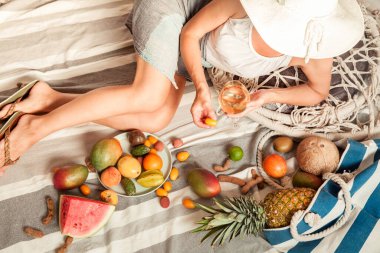 Kız yaz pikniğine uzanmış şarap ve meyvelerle