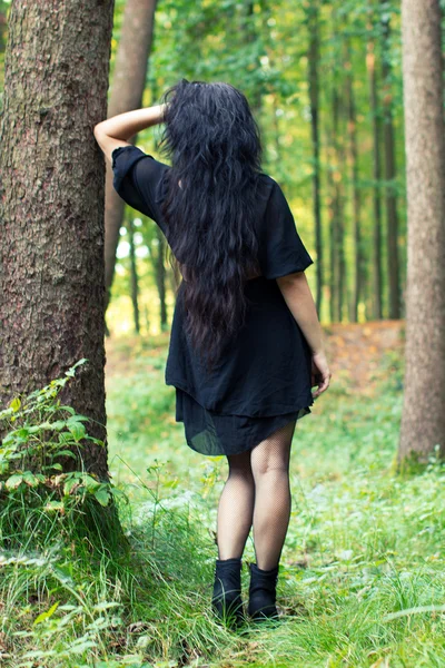 Girl turned around standing and leaning on a tree — Stock Photo, Image