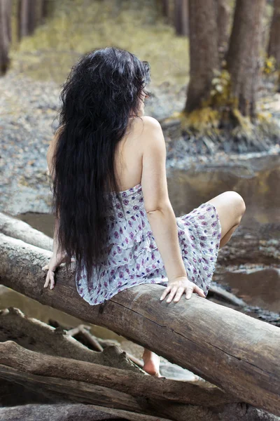 Mädchen sitzt auf einem Baumstamm im Wald — Stockfoto