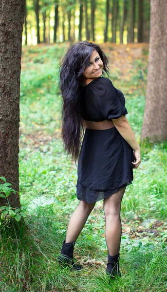 Usmívající se dívka otočí stojící v lese — Stockfoto