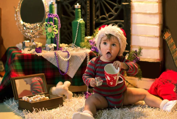 Baby in Santa hat with a cap and gift stuck out her tongue — Stock Photo, Image