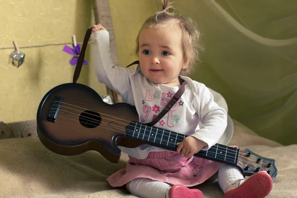 Smiling girl with guitar on the bed — Stock Photo, Image