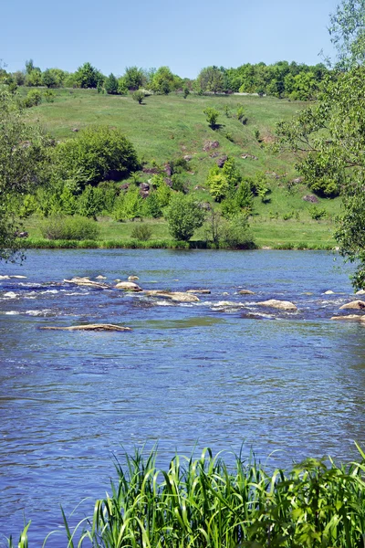 Paysage d'une rivière, collines herbeuses verdoyantes, arbres et ciel — Photo