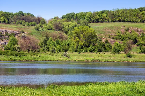 Paysage d'une verdoyante collines herbeuses, arbres, rivière et ciel — Photo