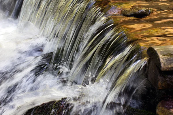 El agua fluye a través de los troncos de madera, cayendo en cascada Imagen de archivo