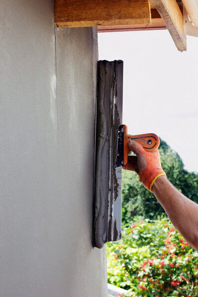 hand in gloves putties a wall by putty knife for facade