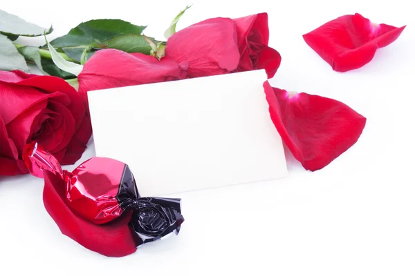 Rose rosse e caramelle con una carta regalo vuota — Foto Stock