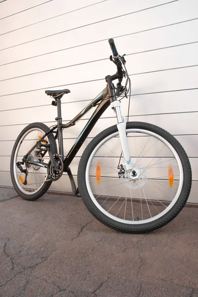 Bicicleta feminina no asfalto crepitado e um fundo listrado — Fotografia de Stock