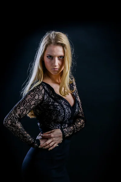 Blond meisje op een zwarte achtergrond in een donkere guipure jurk — Stockfoto