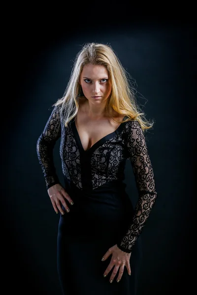 Blond meisje op een zwarte achtergrond in een donkere guipure jurk — Stockfoto