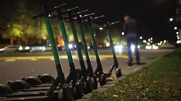 Man rents electric scooter and rides away at night Royalty Free Stock Photos