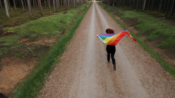 Woman holds large rainbow LGBT flag and runs forward in sign of equal rights aerial