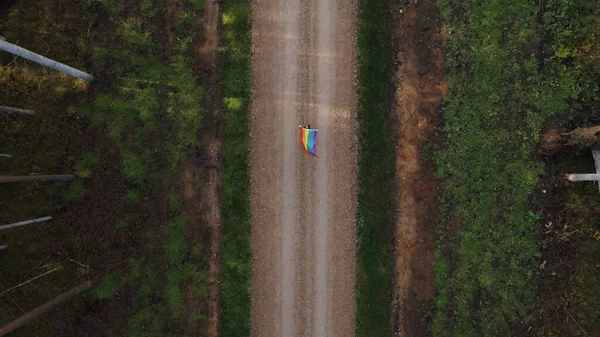 Vista de arriba hacia abajo: Mujer joven bisexual corre con solo colorida bandera LGBT visible — Foto de Stock