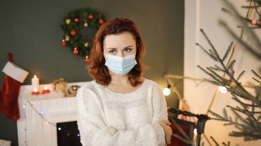 Tıbbi maske takmış yorgun genç bir kadın sana bakıyor.