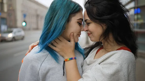 Close view: Jonge brunette vrouw in regenboog armband knuffelt haar schattige vriendin met groen haar — Stockfoto