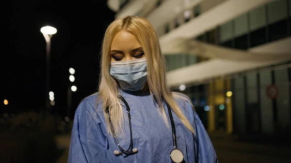 Молодой доктор смотрит в сторону в хирургической маске рядом с больницей — стоковое фото