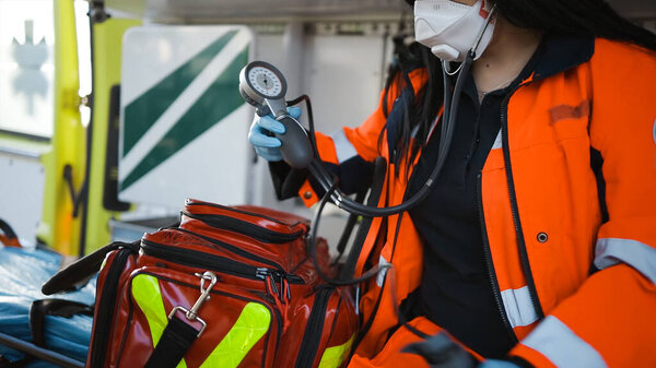 Female paramedic packs sphygmomanometer sitting inside an emergency vehicle