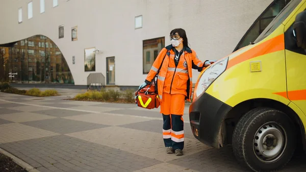 Establishing shot: Paramedic stands near ambulance. Writing on clothes means Urgent care — Stock Photo, Image